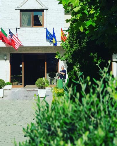 a man sitting in front of a building with flags at Hotel Ambasador Garden in Lezhë