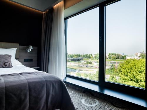 een slaapkamer met een bed en een groot raam bij Q Hotel Plus Kraków in Krakau