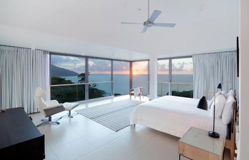 a white bedroom with a bed and a large window at AquaBlu Villa in Victoria