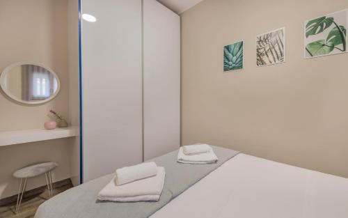 sypialnia z białym łóżkiem i 2 ręcznikami w obiekcie Cosy apartment in the heart of the city centre w mieście Zakintos
