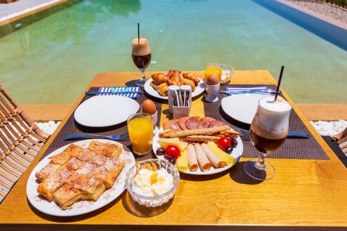a table with breakfast food and drinks on a table by a pool at 180 South Seaside Hotel in Thermisia