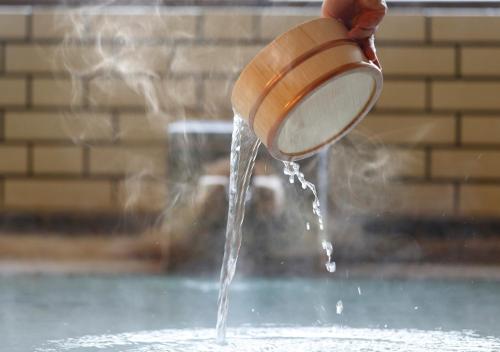 a person is pouring water from a wooden pot at mt. inn(マウントイン） in Nihommatsu