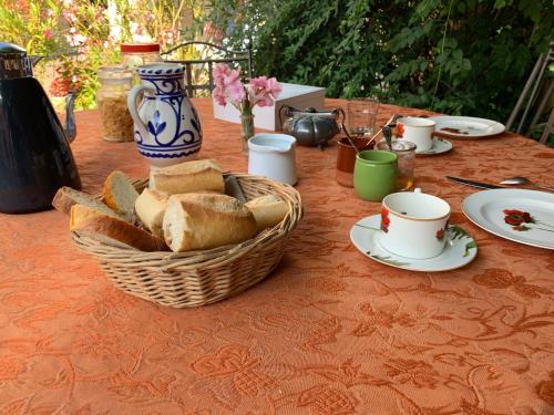 una mesa con una cesta de pan y tazas. en La Sarrasine, en Villes-sur-Auzon