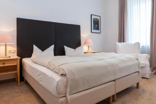 1 Schlafzimmer mit einem großen weißen Bett und 2 Stühlen in der Unterkunft BRISTOL Hotel Bad Kissingen in Bad Kissingen