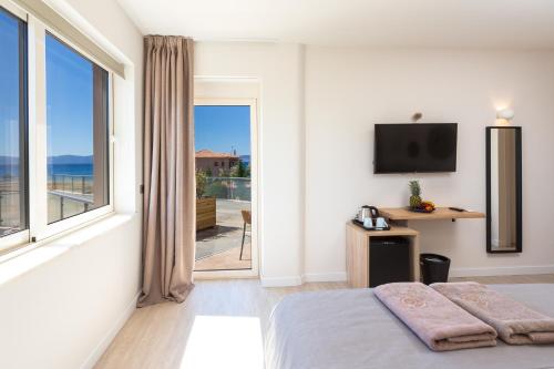 a bedroom with a bed and a large window at 180 South Seaside Hotel in Thermisia