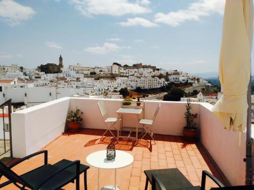 a balcony with chairs and tables and a view of a city at La Guarida de Vejer Casa Rural in Vejer de la Frontera