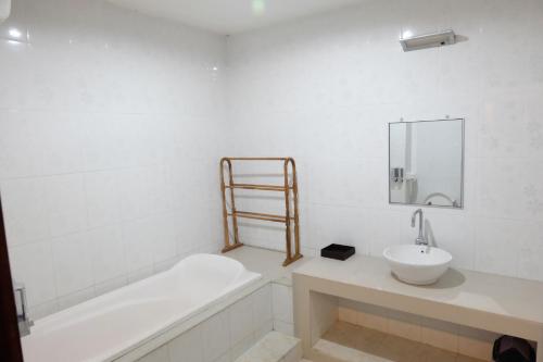 a bathroom with a sink and a bath tub and a mirror at Taman Sari Tagtag in Sanur