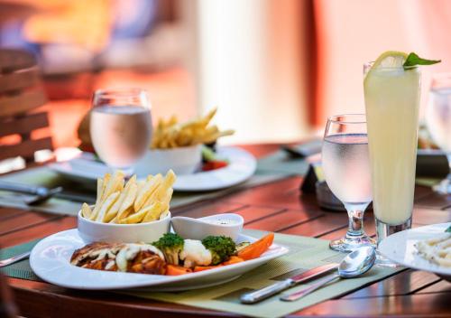 a wooden table with plates of food and a drink at Lancaster Tamar Hotel- Hadath in Beirut