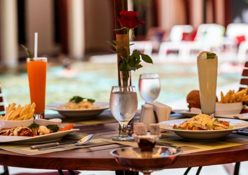 a wooden table with plates of food and drinks at Lancaster Tamar Hotel- Hadath in Beirut