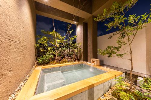 a hot tub in a garden next to a building at cyashitsu ryokan asakusa in Tokyo