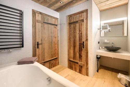Łazienka z wanną i drewnianymi drzwiami w obiekcie LISA-Chalets w mieście Flachau