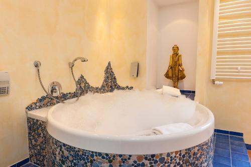 eine Badewanne im Bad mit einer Statue in der Unterkunft BRISTOL Hotel Bad Kissingen in Bad Kissingen