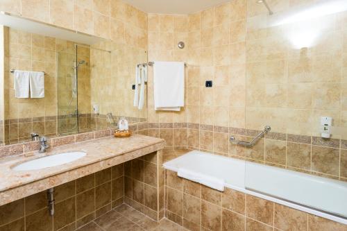 a bathroom with a tub and a sink and a mirror at Tiara Beach - All Inclusive in Sunny Beach