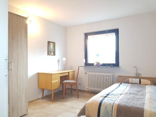 een slaapkamer met een bed, een bureau en een raam bij Zimmervermietung St.Wendel in Sankt Wendel