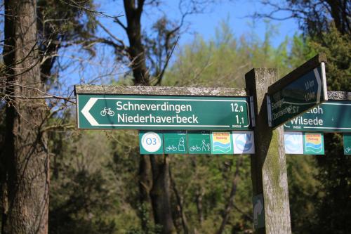 two green street signs on a wooden pole at Landhotel Hof Barrl in Schneverdingen