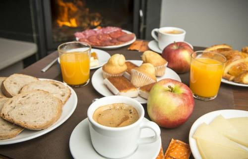 a table with plates of breakfast foods and cups of coffee at Hotel portico in Fonsagrada