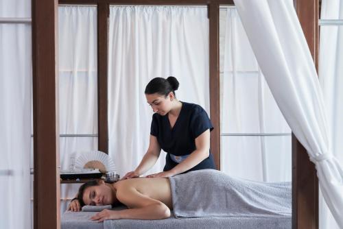 a woman laying on a mans back in a bed at Rodos Princess Beach Hotel in Kiotari