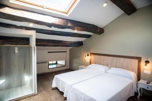 a bedroom with a large white bed and a skylight at Hotel portico in Fonsagrada