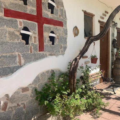 a stone wall with a tree in front of a building at S'Imbragu Farm B&B in Tortolì