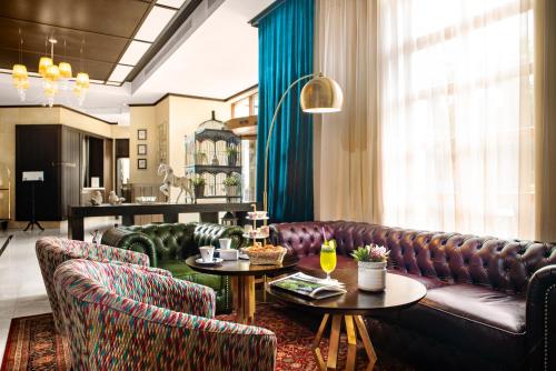 a living room with a leather couch and two tables at Epoque Hotel - Relais & Chateaux in Bucharest