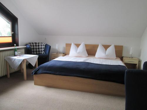 a bedroom with a bed and a chair at Hotel Skandinavia in Sankt Andreasberg