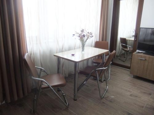 a dining room table with chairs and a vase of flowers on it at APARTAMENT REBEKA in Mamaia Nord