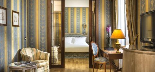 a hotel room with a bed and a desk and a television at Sina De La Ville in Milan