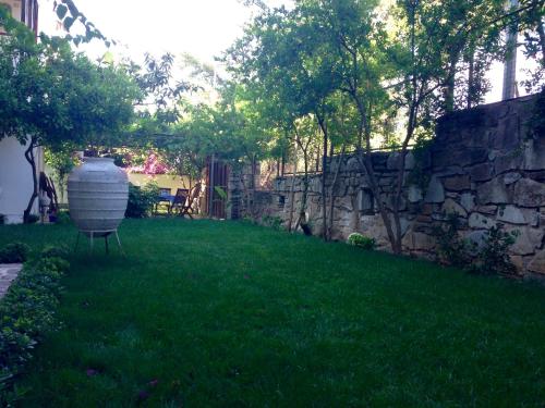 a yard with a stone wall and a vase in the grass at Totelya Hotel in Akyaka