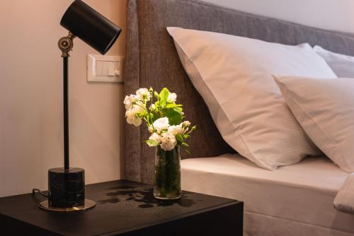a vase of flowers on a table next to a bed at Hotel Florian&Godler in Karlovac