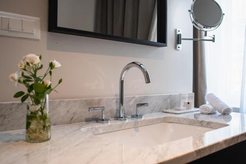 a bathroom sink with a vase of flowers and a mirror at Hotel Florian&Godler in Karlovac