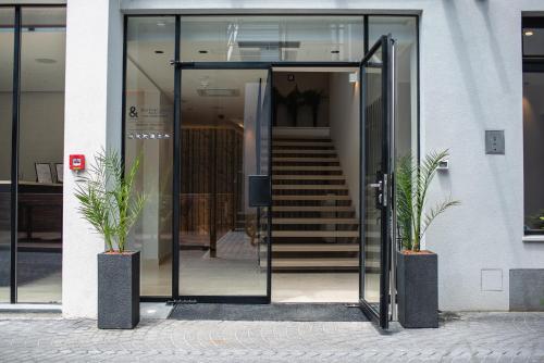an open glass door of a building with two potted plants at Hotel Florian&Godler in Karlovac