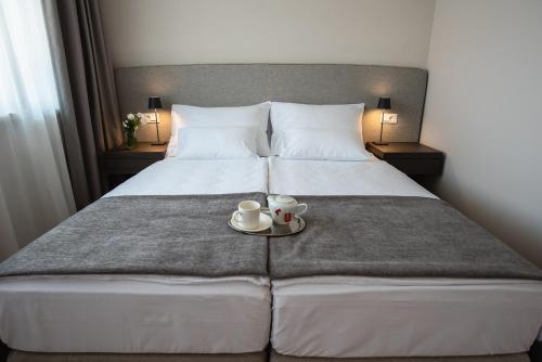 a hotel room with a bed with a tray with a cup and saucer at Hotel Florian&Godler in Karlovac