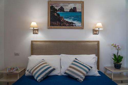 1 dormitorio con 1 cama con 2 almohadas y una pintura en la pared en Casa Lucia Relaxing rooms en Anacapri