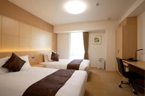 a hotel room with two beds and a desk at Shizutetsu Hotel Prezio Shizuoka Ekinan in Shizuoka