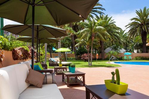 eine Terrasse mit einem Sofa, einem Sonnenschirm und einem Pool in der Unterkunft Sol Puerto de la Cruz Tenerife in Puerto de la Cruz