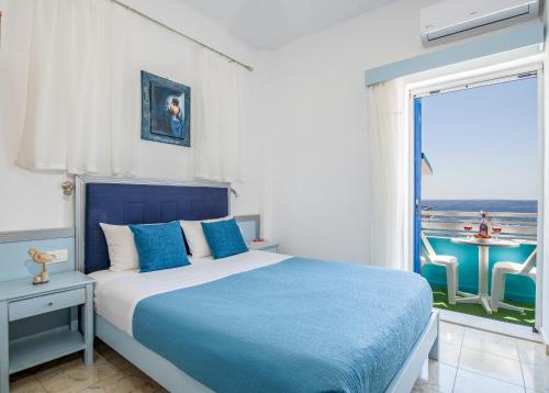 a bedroom with a blue and white bed and a window at Klima Rooms in Palaiochora