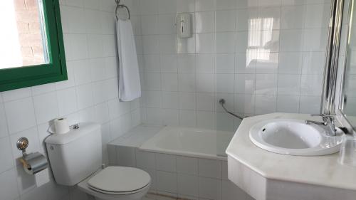 a white bathroom with a toilet and a sink at Sabiñanigo Camp & Hotel in Sabiñánigo