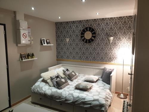 a bedroom with a bed with pillows and a clock on the wall at Appartement Médicis avec Garage in Honfleur