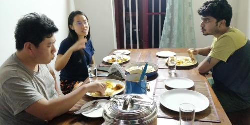 a group of people sitting around a table eating food at Anamala Serenity Homestay Kerala in Lakkidi