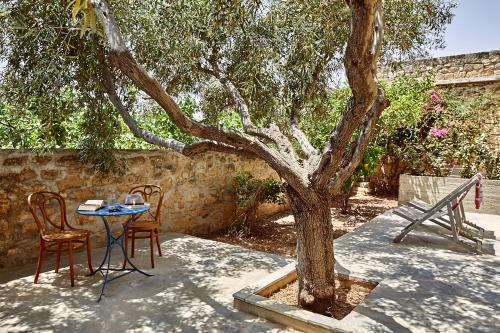 a table and two chairs next to a tree at Nikolaou Art Residence in Aegina Town