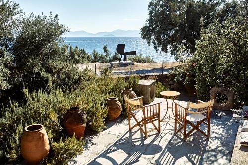 a patio with chairs and a table with a view of the water at Nikolaou Art Residence in Aegina Town