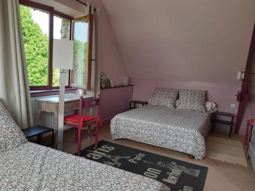 a bedroom with two beds and a desk and a window at La grange des lisières in Rouvres