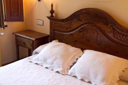 a bed with two white pillows and a wooden headboard at Posada La Colodra in Los Tojos