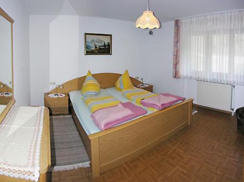 a bedroom with a bed with yellow and pink pillows at Vogthof Wohnung Schneckenhus in Lautenbach