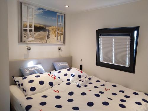 Un dormitorio con una cama con sábanas de lunares y una ventana. en Hausboot Leukermeer Well, en Well