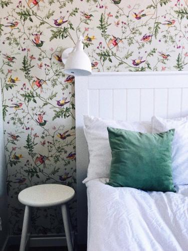 a bed with a green pillow next to a wall with flowers at Arkösunds Hotell in Arkösund