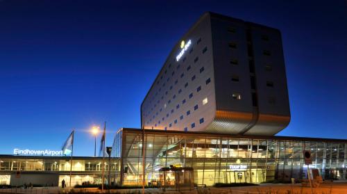 a building at night with a tall building at Tulip Inn Eindhoven Airport in Eindhoven