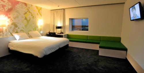 a hotel room with a bed and a green bench at Tulip Inn Eindhoven Airport in Eindhoven