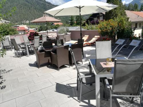a patio with tables and chairs and an umbrella at Haus Tirol Appartements in Ried im Oberinntal