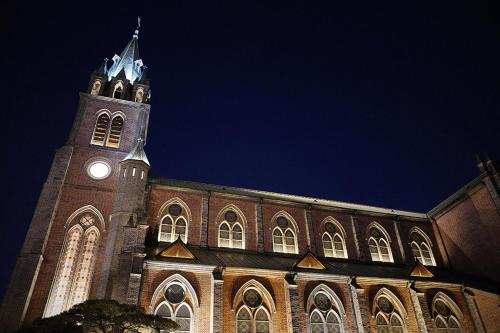 a large brick building with a clock tower at night at Hotel Lumia Myeongdong in Seoul